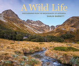 Cover of the book 'A Wild Life: Photographs from the Backcountry of Aotearoa' by Shaun Barnett, featuring a landscape photograph of a mountainous backdrop with a river and vegetation.